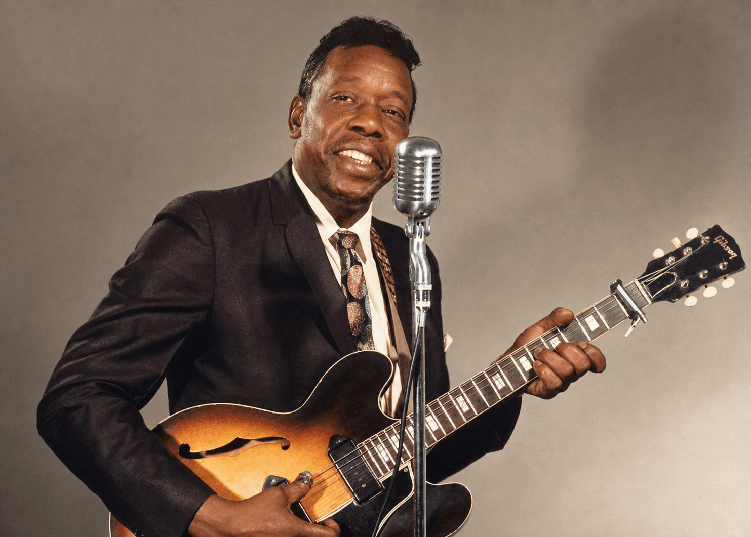 Slim Harpo performing with guitar and microphone beside his gold signature